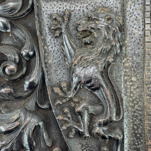 155 - A carved oak heraldic panel. 19th century, the central shield with a lion rampant, within scrolling ... 