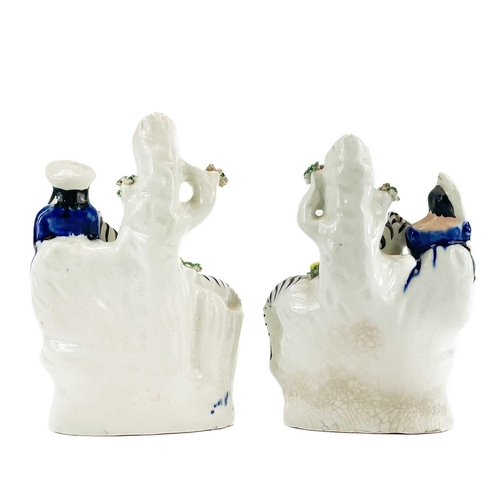 165 - A pair of Victorian Staffordshire spill vases of zebras. Each with a fruit filled pannier and attend... 