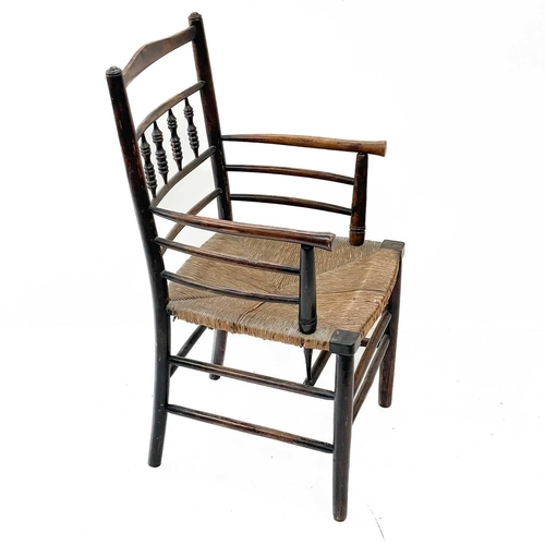 213 - A stained beech elbow chair. 19th century, with turned spindle and rail back, seagrass seat and turn... 