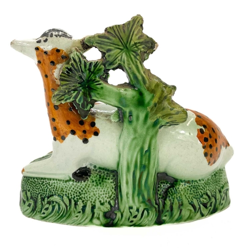 243 - A Staffordshire pearlware figure of a deer. Early 19th century, with a bocage back, on a mound base,... 