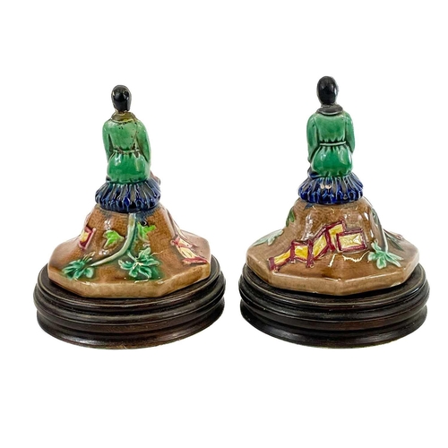 248 - A pair of Majolica vase covers on stands. Modelled with an oriental figure in a garden landscape, ov... 