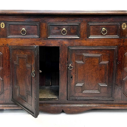 256 - A Jacobean oak dresser base. With two long and one short central drawer above two cupboard doors on ... 