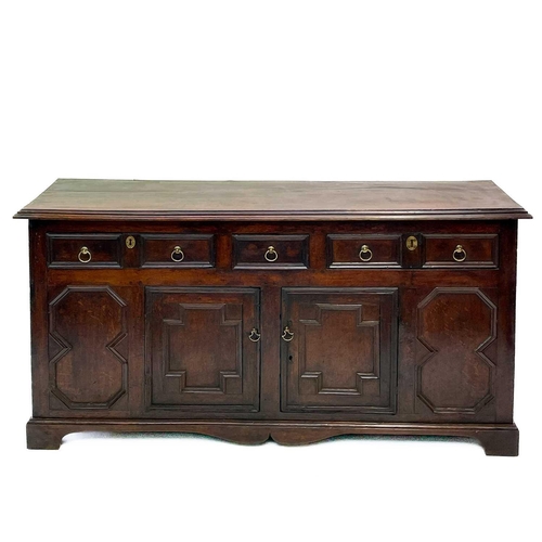 256 - A Jacobean oak dresser base. With two long and one short central drawer above two cupboard doors on ... 