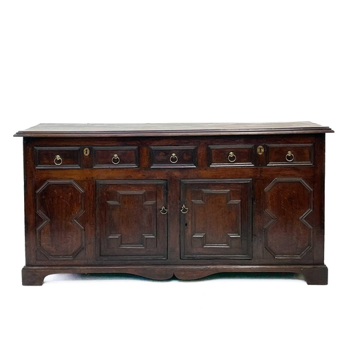 256 - A Jacobean oak dresser base. With two long and one short central drawer above two cupboard doors on ... 