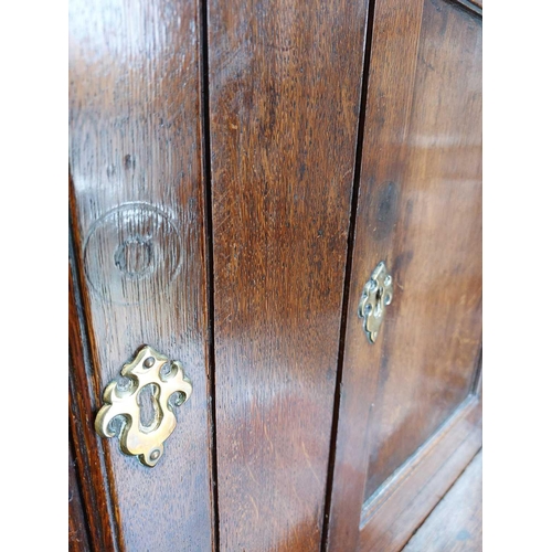 3 - A late George III Welsh oak cupboard Deuddarn The cornice with drop finials above two doors, the pro... 