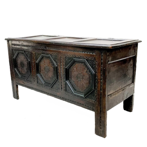 44 - A 17th century oak coffer. With three carved front panels, lift up the rectangular lid on block feet... 