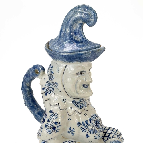 52 - A Deflt blue and white character jug and cover as Mr Punch. Circa 1900, the portly figure modelled s... 