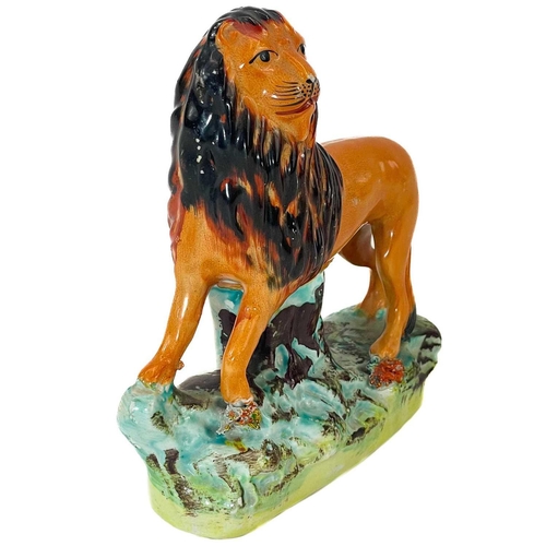 6 - A Victorian Staffordshire figure of a lion. Standing four square on a naturalistic base, height 16.5... 