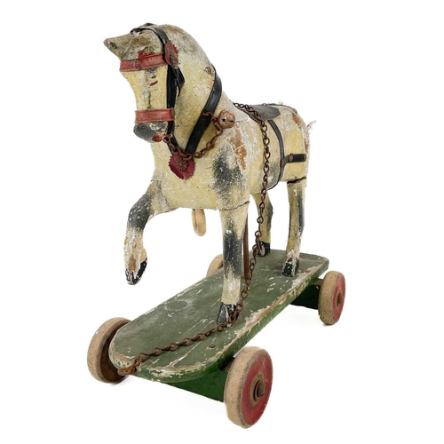 64 - A child's painted toy pull-along horse. Early 20th century, piebald decoration, on a green painted b... 