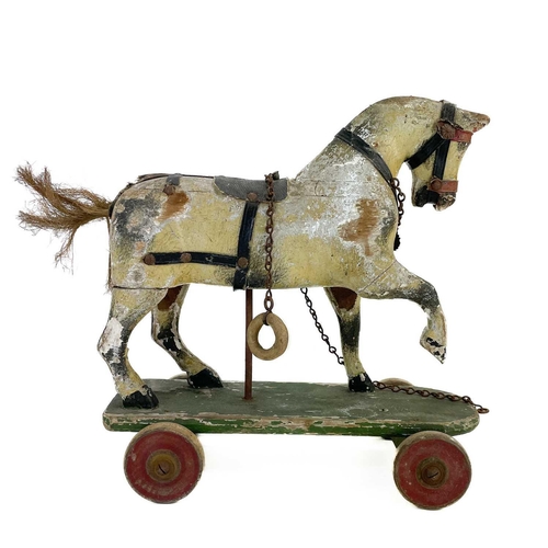 64 - A child's painted toy pull-along horse. Early 20th century, piebald decoration, on a green painted b... 