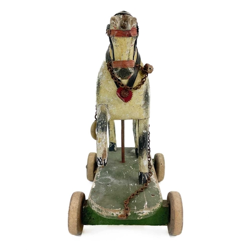 64 - A child's painted toy pull-along horse. Early 20th century, piebald decoration, on a green painted b... 