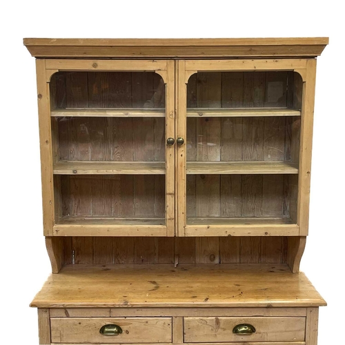 71 - A Victorian pine dresser. The upper part with two glazed doors, the lower part with two drawers and ... 