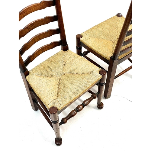 87 - Six 20th century ash and oak ladder back chairs. With drop in rush seats and two carvers. (6)Stirdy,... 