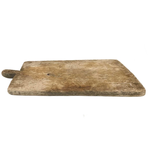 99 - A late 19th century large chopping board. Carved with a small handle, width 80cm depth 38cm.