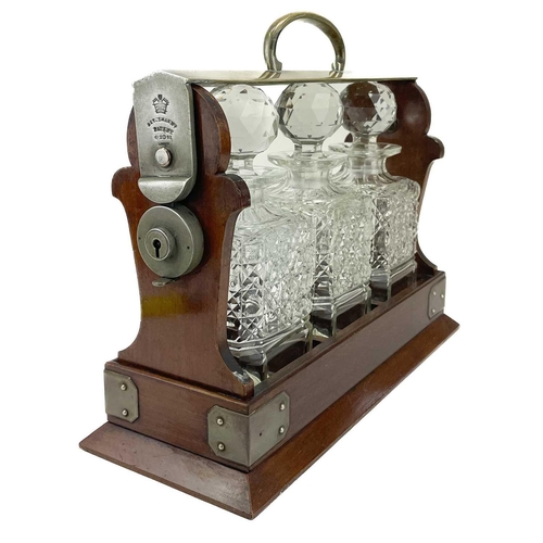 105 - A Betejeman's patent three bottle mahogany tantalus. With silver plated fittings, and stamped marks,... 