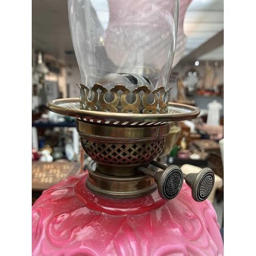 115 - A Victorian brass oil lamp with a glass oil reservoir and cranberry shade. With circular base, mould... 