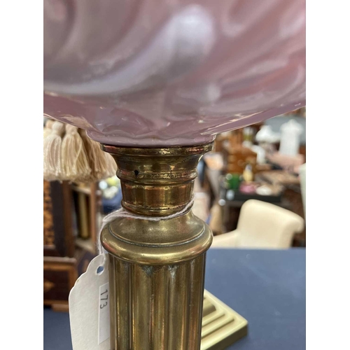 115 - A Victorian brass oil lamp with a glass oil reservoir and cranberry shade. With circular base, mould... 