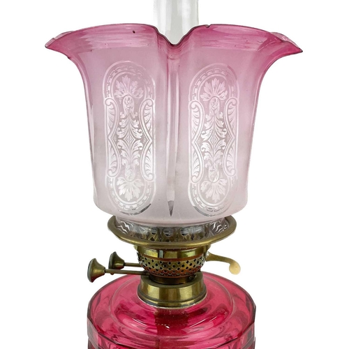 119 - A Victorian brass oil lamp with a cranberry reservoir and cranberry glass shade. Raised on circular ... 