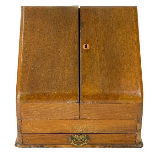 143 - A late Victorian slope front stationary cabinet. With two doors enclosing a fitted interior and a dr... 