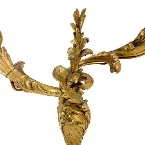 166 - A French ormolu twin branch candelabrum. 19th century, in the rococo taste with leafy scrolls and in... 