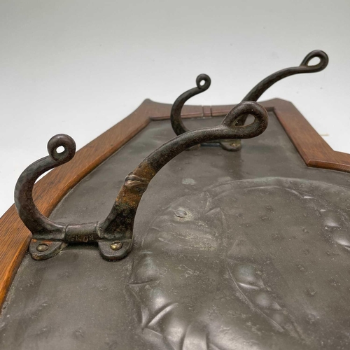 168 - An Arts and Crafts pewter and oak coat rack. With beaten decoration of two fish, and fitted three ca... 