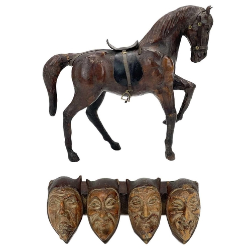 18 - A leather model of a harnessed horse. With inset glass eyes, height 30cm, together with a carved tre... 