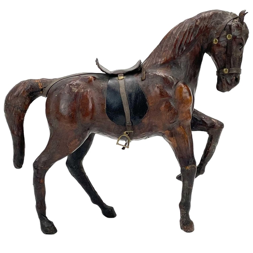 18 - A leather model of a harnessed horse. With inset glass eyes, height 30cm, together with a carved tre... 