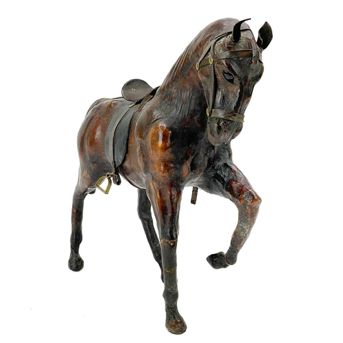 18 - A leather model of a harnessed horse. With inset glass eyes, height 30cm, together with a carved tre... 