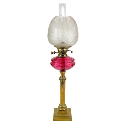 202 - A Victorian brass oil lamp with glass shade. With cranberry glass oil reservoir and an etched glass ... 