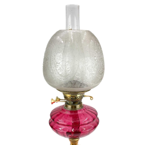 202 - A Victorian brass oil lamp with glass shade. With cranberry glass oil reservoir and an etched glass ... 