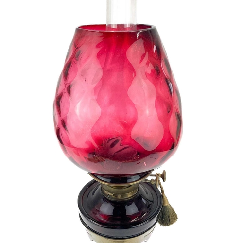 205 - A Victorian brass oil lamp with a cranberry glass shade. Raised on a circular base, with a glass oil... 