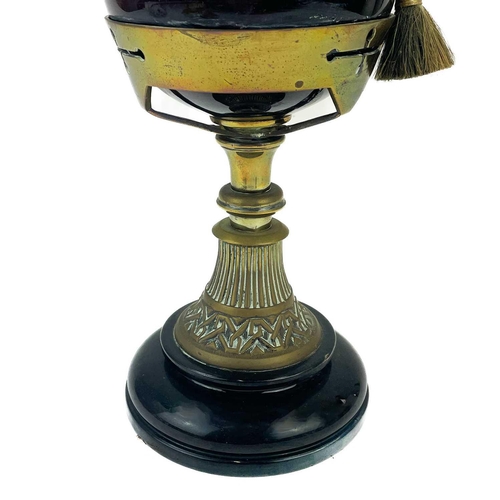 205 - A Victorian brass oil lamp with a cranberry glass shade. Raised on a circular base, with a glass oil... 