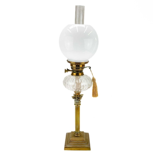 21 - A Victorian brass oil lamp with a clear glass oil reservoir and white glass shade. Raised on a squar... 