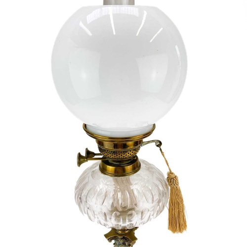 21 - A Victorian brass oil lamp with a clear glass oil reservoir and white glass shade. Raised on a squar... 