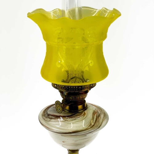 244 - A Victorian brass oil lamp with marble glass reservoir. Yellow glass shade, height 59cm.