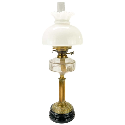 31 - A Victorian brass oil lamp with a glass reservoir and white glass shade. Raised on a circular base, ... 