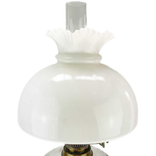 31 - A Victorian brass oil lamp with a glass reservoir and white glass shade. Raised on a circular base, ... 