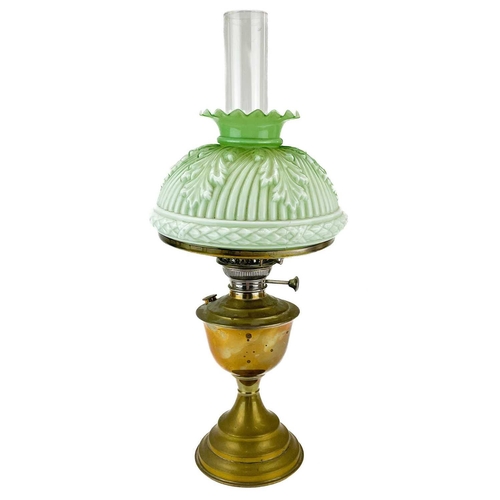 44 - A Victorian brass oil lamp with a moulded green glass shade. With a brass oil reservoir and a domed ... 