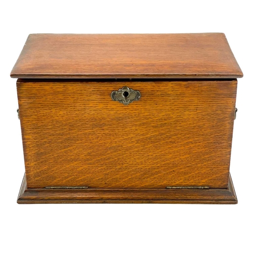 50 - An Edwardian oak stationery cabinet. With rising lid and drop front with a fold-down writing surface... 