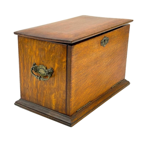 50 - An Edwardian oak stationery cabinet. With rising lid and drop front with a fold-down writing surface... 