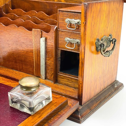 50 - An Edwardian oak stationery cabinet. With rising lid and drop front with a fold-down writing surface... 