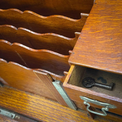 50 - An Edwardian oak stationery cabinet. With rising lid and drop front with a fold-down writing surface... 