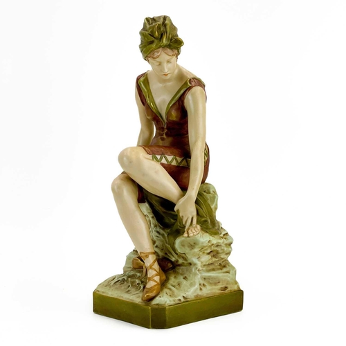 531 - A Royal Dux figure of a bather. Early 20th century, wearing a coloured swimsuit and seated on a rock... 