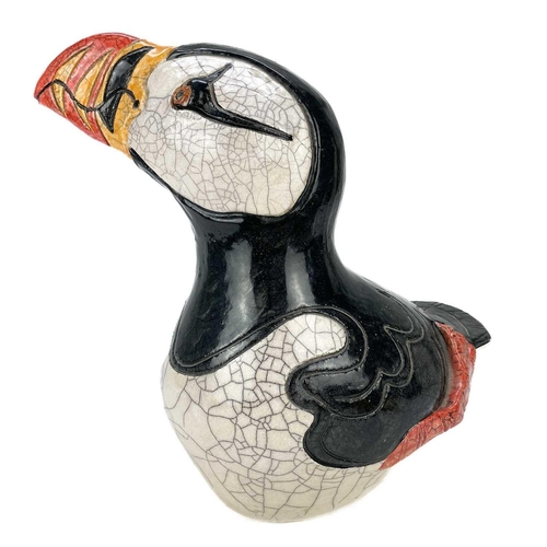 557 - A Jennie Hale Raku glazed figure of a puffin. Signed to base, height 24cm. There is a glaze flake on... 