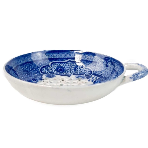 577 - A blue printed pearlware egg drainer. Circa 1810, with intricately pierced base and applied handle, ... 