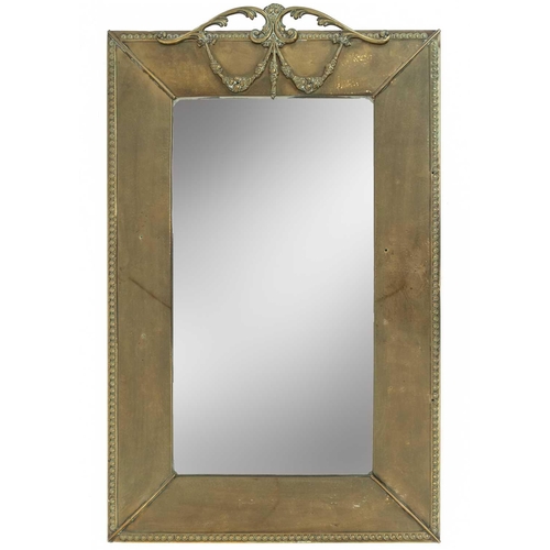 602 - An Edwardian brass framed rectangular wall mirror. With leafy scroll and floral swag surmount, and f... 