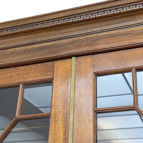 629 - A late Victorian breakfront bookcase. The moulded cornice above astragal glazed doors enclosing adju... 