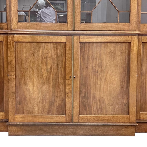 629 - A late Victorian breakfront bookcase. The moulded cornice above astragal glazed doors enclosing adju... 