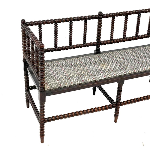 633 - A late Victorian stained beech bobbin turned settee. Of small proportions, with open back and padded... 