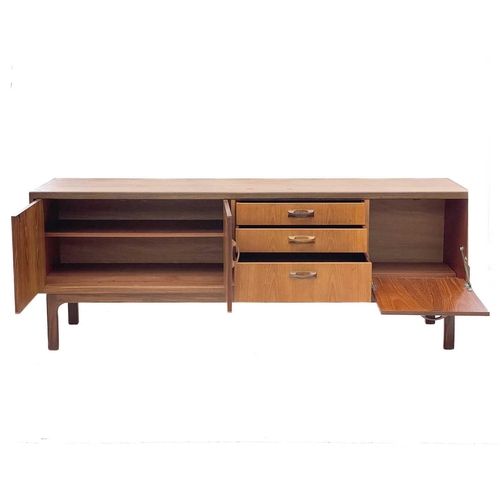 666 - A teak G Plan Sierra sideboard. With three off centre drawers flanked by a drop-down door and twin c... 